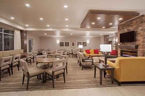 a waiting room with tables and chairs and a fireplace at Staybridge Suites Rapid City - Rushmore, an IHG Hotel in Rapid City