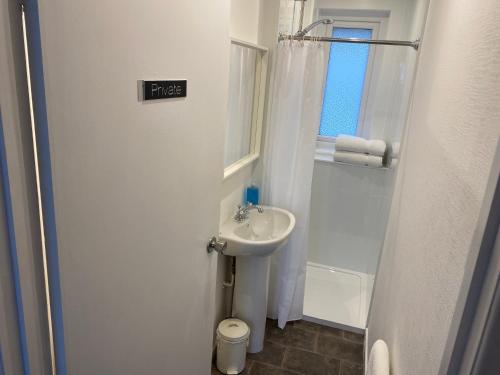 niewielka, biała łazienka z umywalką i oknem w obiekcie Loch Eyre Shepherd Hut w mieście Portree