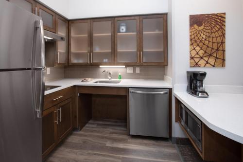 a kitchen with wooden cabinets and a stainless steel refrigerator at Staybridge Suites Rapid City - Rushmore by IHG in Rapid City