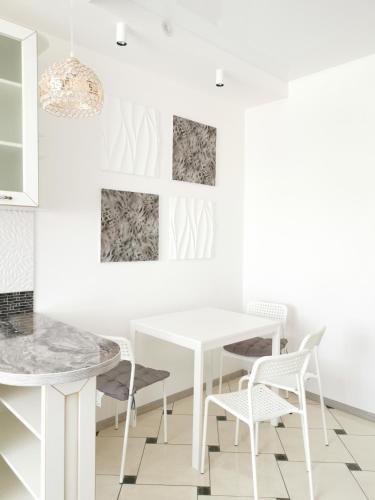 a white dining room with a white table and chairs at Manufactura apartments 2 in Sumy