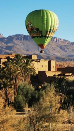 a green hot air balloon flying over a desert at Auberge Le Festival Todra Gorge in Aït Baha