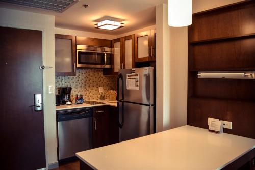 a kitchen with a stainless steel refrigerator and cabinets at Staybridge Suites Puebla by IHG in Puebla