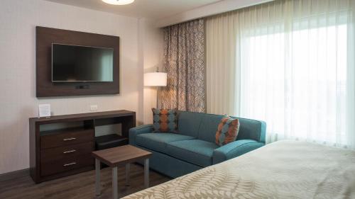 a hotel room with a bed and a couch and a tv at Staybridge Suites Puebla by IHG in Puebla