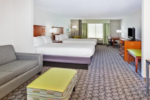 フェニックス・シティにあるHoliday Inn Express Phenix City-Fort Benning, an IHG Hotelのベッド2台とソファが備わるホテルルームです。