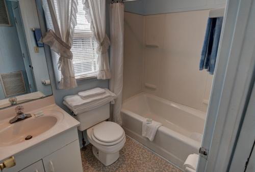 a bathroom with a toilet and a sink and a tub at Outer Banks Motel in Buxton