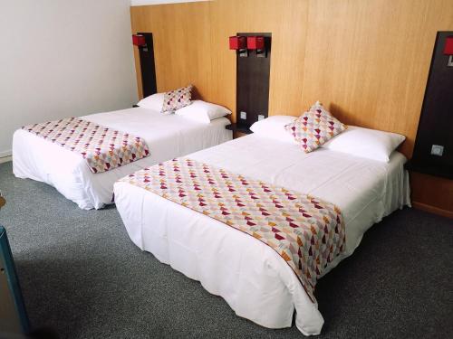 2 camas en una habitación de hotel con sábanas blancas en Hôtel Restaurant de France, en Castelnaudary