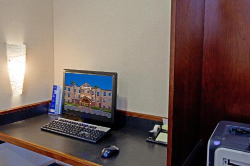 a desk with a computer monitor and a keyboard and mouse at Staybridge Suites Palmdale by IHG in Palmdale