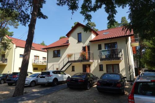 a building with cars parked in a parking lot at Kama Apartament Pobierowo in Pobierowo