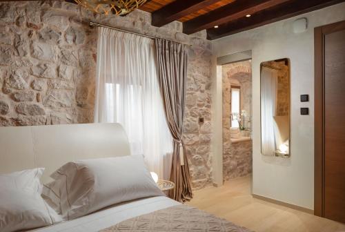 - une chambre avec un lit blanc et un mur en pierre dans l'établissement Luxury Rooms MA de Dominis, à Split