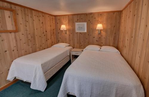 two beds in a room with wooden walls at Outer Banks Motel in Buxton