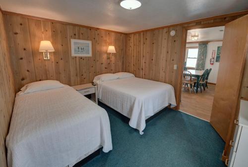 two beds in a room with wooden walls at Outer Banks Motel in Buxton