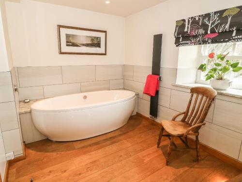 eine weiße Badewanne im Bad mit Stuhl in der Unterkunft Bay Horse Cottage in Skipton