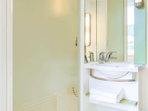 een badkamer met een wastafel en een spiegel bij ibis budget Issy Les Moulineaux Paris Ouest in Issy-les-Moulineaux