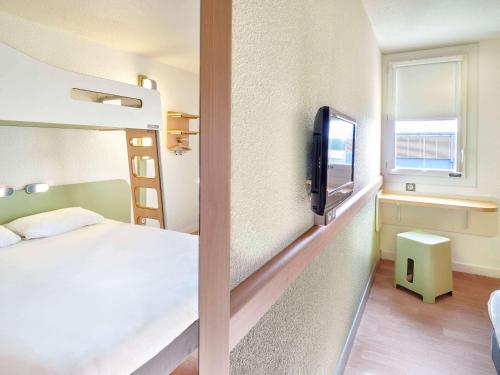 een slaapkamer met een bed en een tv in een kamer bij ibis budget Saint Paul Les Dax in Saint-Paul-lès-Dax