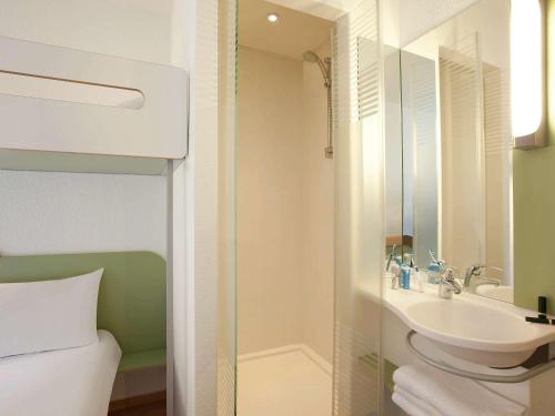 La salle de bains est pourvue d'un lavabo, d'une douche et de toilettes. dans l'établissement ibis budget Tours Nord, à Tours