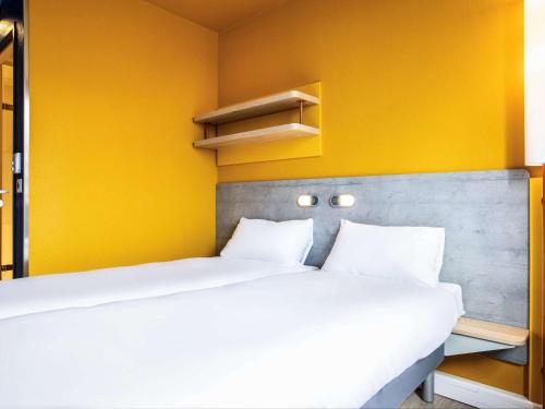 a bedroom with two beds and a yellow wall at ibis budget Fontainebleau Avon in Avon