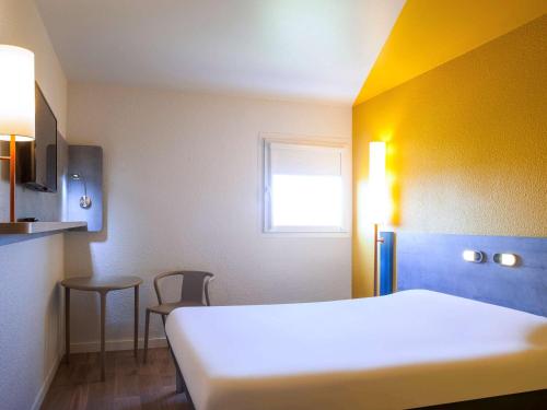 a room with a bed and a table and a window at ibis budget Fontainebleau Avon in Avon