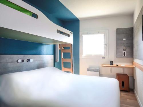 Hotel Ibis Budget Abbeville في آبّيفيل: غرفة نوم بسرير ابيض وجدار ازرق