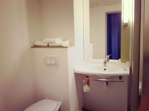 une salle de bain avec un lavabo, des toilettes et un miroir dans l'établissement ibis Budget Arles Palais Des Congres, à Arles