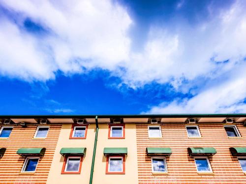 a brick building with a cloudy blue sky in the background at Ibis Budget - Casula Liverpool in Liverpool