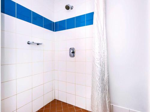 a bathroom with a shower with blue and white tiles at Ibis Budget - Casula Liverpool in Liverpool
