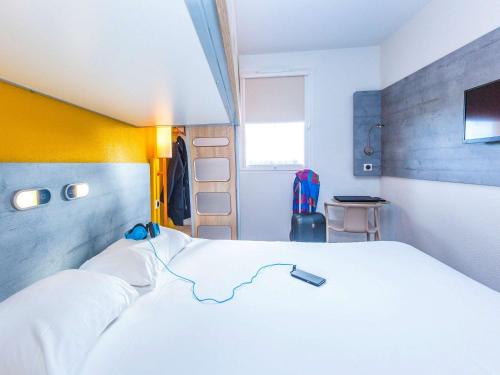 Un dormitorio con una gran cama blanca con aigil en Ibis Budget Marmande, en Marmande