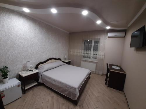 1 dormitorio con 1 cama, 2 mesas y TV en Mini-hotel en Umanʼ
