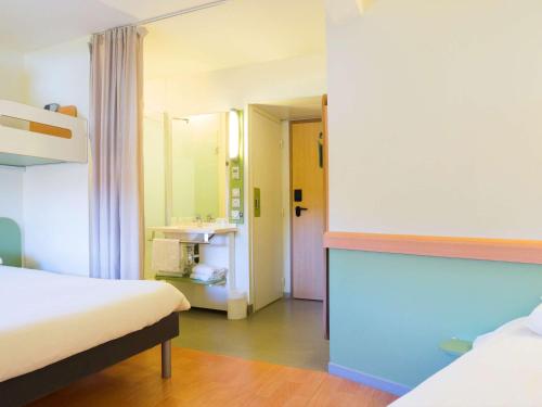 a room with two beds and a bathroom with a sink at Ibis Budget Valence Sud in Valence