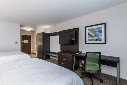 a hotel room with a desk and a bed and a chair at Holiday Inn Express & Suites- South Bend Casino by IHG in South Bend