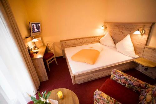 a small room with a bed and a chair at Hotel Am Kamin in Kaufbeuren