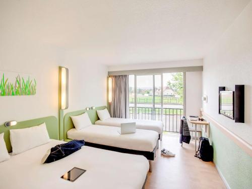 a hotel room with two beds and a couch at ibis budget Pau Lescar in Lescar