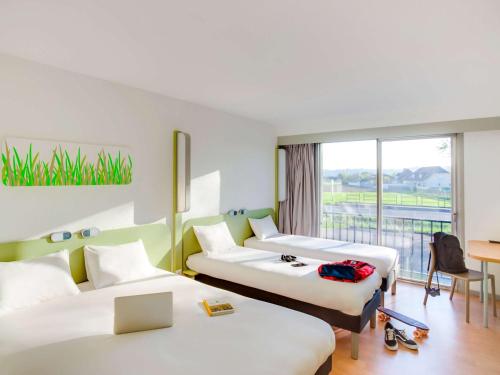 a hotel room with three beds and a balcony at ibis budget Pau Lescar in Lescar