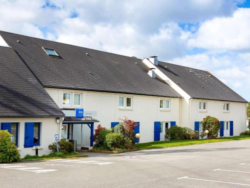 a large white house with blue doors and a street at Ibis budget Lorient Caudan in Caudan