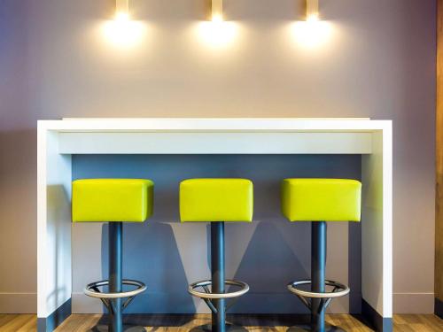 two yellow stools in front of a fireplace at Ibis budget Lorient Caudan in Caudan