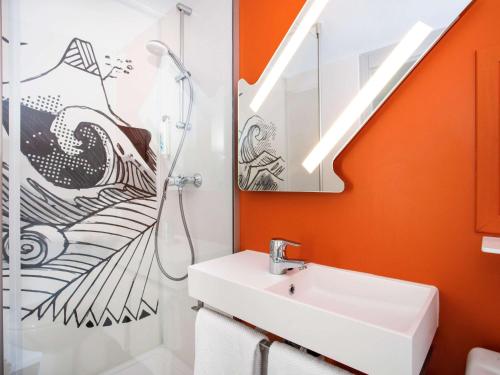 an orange bathroom with a sink and a shower at Ibis budget Lorient Caudan in Caudan