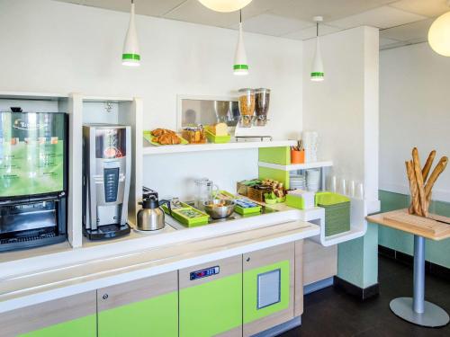 a kitchen with green and white cabinets and a refrigerator at ibis budget Aeroport le Bourget Garonor in Le Blanc-Mesnil