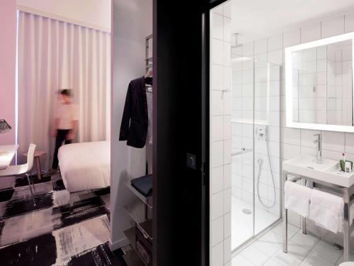 a bathroom with a shower and a sink and a bed at Mama Shelter Bordeaux Centre in Bordeaux