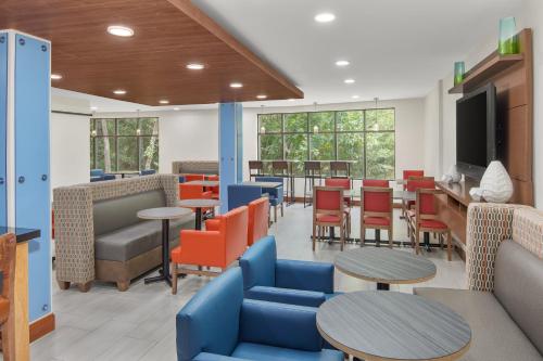 a waiting room with tables and chairs and a tv at Holiday Inn Express & Suites - Hardeeville-Hilton Head by IHG in Hardeeville