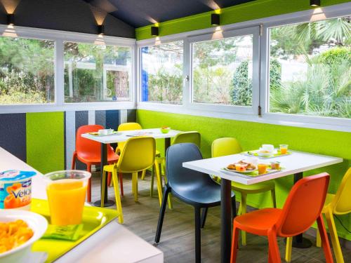 un ristorante con sedie e tavoli colorati e finestre di Ibis Budget Béziers Est La Giniesse a Béziers