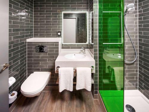 a bathroom with a sink and a toilet and a mirror at ibis Styles London Ealing in London