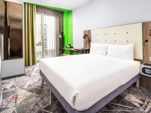 a large white bed in a room with a green wall at ibis Styles London Ealing in London