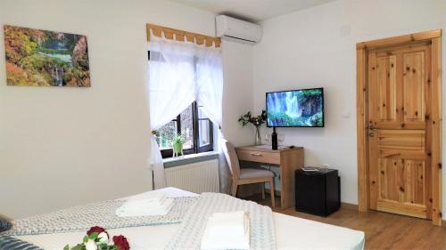 a bedroom with a bed and a desk and a television at Plitvice Streaming in Prijeboj