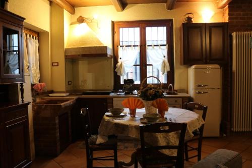 a kitchen with a table with chairs and a refrigerator at Cascina Merlanetta in Alessandria