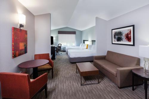 um quarto de hotel com uma cama, um sofá e mesas em Holiday Inn Express Hotel and Suites Shreveport South Park Plaza, an IHG Hotel em Shreveport