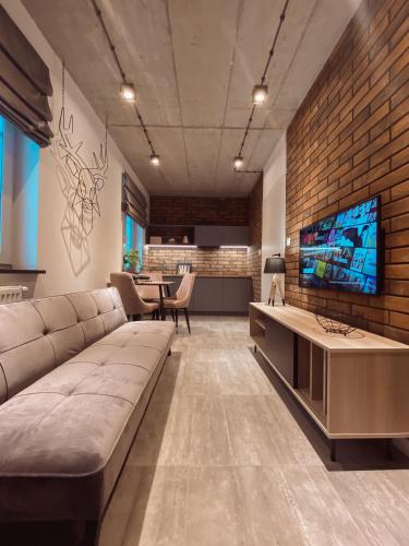 a living room with a large couch and a tv at THE LOFT - Garncarska 1 in Piotrków Trybunalski
