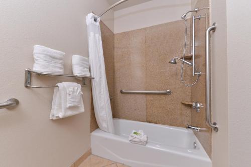 a bathroom with a tub and a shower with towels at Holiday Inn Express Hotel & Suites Sherman Highway 75 by IHG in Sherman