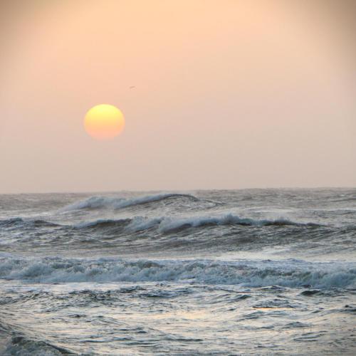 a sun setting over the ocean with waves at Galerazambahostal in Galerazamba