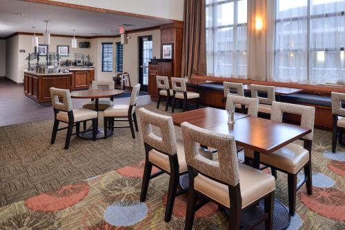 a restaurant with tables and chairs and a kitchen at Staybridge Suites Rochester by IHG in Rochester