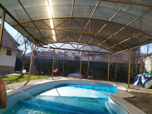 an overhead swimming pool with a metal roof at Къща за гости с минерална вода "Терма Асклепий" in Kyustendil
