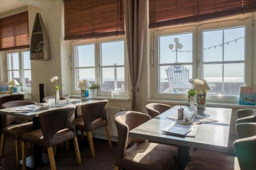 a dining room with tables and chairs and windows at AKZENT Strandhotels Seestern, Delphin & Lachs in Wilhelmshaven